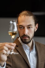 Young man examining glass of wine
