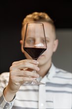 Young man examining glass of wine