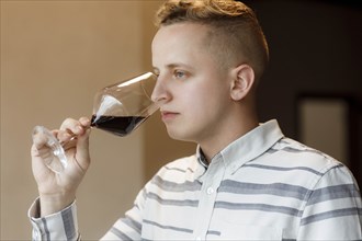 Young man smelling wine in glass at tasting