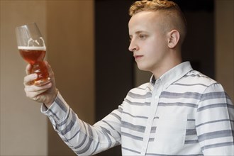 Young man examining glass of beer
