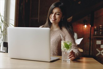 Woman sitting in restaurant with laptop