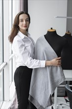 Fashion designer working with dressmaker's model in studio