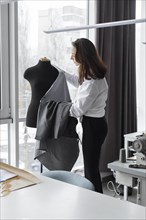 Fashion designer working with dressmaker's model in studio