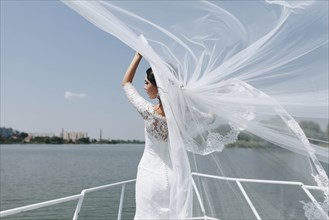 Bride with windswept veil on boat