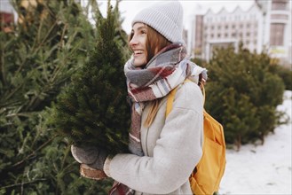 Young woman carrying small Christmas tree