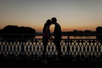 Silhouettes of young couple kissing at sunset