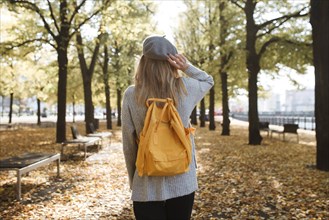 Young woman with yellow backpack in park in Berlin, Germany