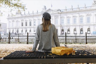 Young woman sitting on park bench near German Historical Museum in Berlin, Germany