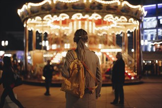 Young woman by carousel at night