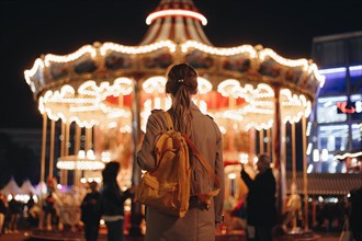 Young woman by carousel at night