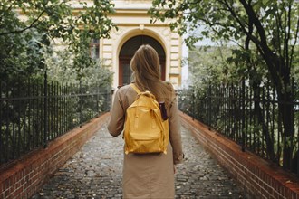 Young woman with yellow backpack walking in park