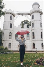 Woman holding red umbrella by Schloss Pfaueninsel in Potsdam, Germany