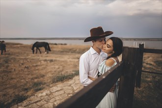 Young couple embracing in field by horses