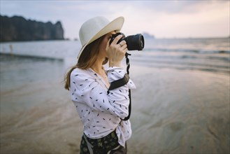Young woman photographing on beach in Krabi, Thailand