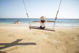 Young woman on swing at beach