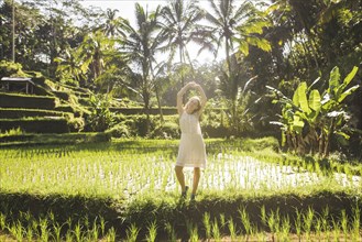 Young woman wearing white dress in rice paddy in Bali, Indonesia