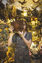 Young woman holding Barong mask in store in Bali, Indonesia