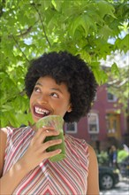 Woman drinking green juice under tree