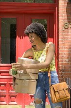 Woman carrying cardboard boxes and green juice
