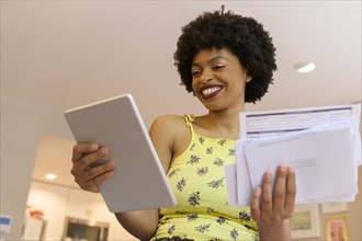 Smiling young woman holding digital tablet and bills