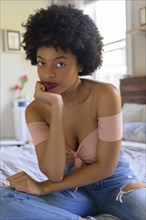 Young woman wearing off shoulder top sitting on  bed