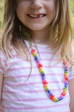 Smiling girl with missing tooth wearing necklace