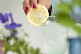 Woman putting lemon slice on glass of water