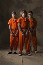 Boys in prisoner jumpsuits and handcuffs