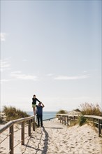 Father helping his son walking on fence on beach