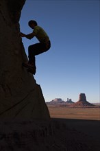 Silhouette of man rock climbing in Monument Valley Navajo Tribal Park, USA