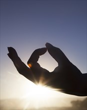Silhouette of woman's hand practicing yoga at sunset