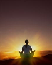 Woman meditating at sunset