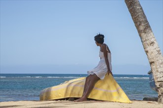 Woman sitting on boat under tree on beach in Las Terrenas, Dominican Republic