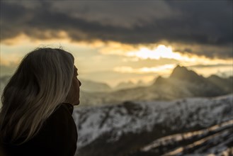 Mature woman by mountains at sunset in Dolomites, Italy