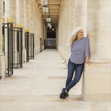 Woman leaning on column of Palais-Royal in Paris, France