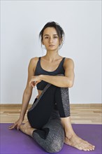 Woman wearing sportswear sitting on yoga mat