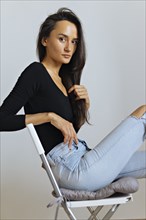 Woman wearing black top and ripped jeans on chair