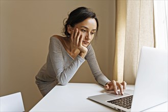 Woman leaning on table using laptop