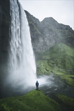 Man standing by Seljalandsfoss waterfall in Iceland