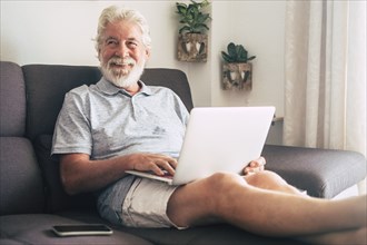 Smiling senior man using laptop on sofa