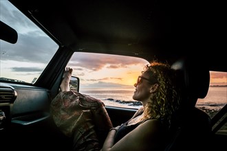 Woman in car with her legs raised watching sunset