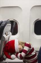 Girl wearing Santa hat sleeping on airplane