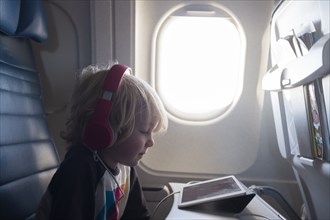 Boy watching digital tablet on airplane