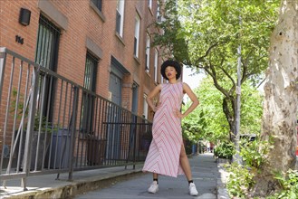 Woman wearing striped dress by brick townhouses
