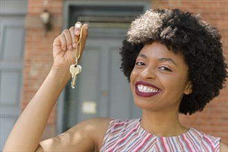 Smiling young woman holding keys
