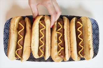 Woman's hand taking hot dog off of tray