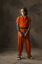 Boy in prisoner jumpsuit and handcuffs