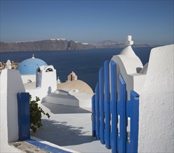 Open blue gate by whitewashed church in Santorini, Greece