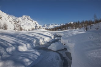 Frozen river in snow covered mountainous landscape in Alpe Devero, Italy