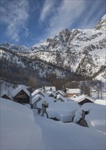 Snow covered village by mountain in Alpe Devero, Italy